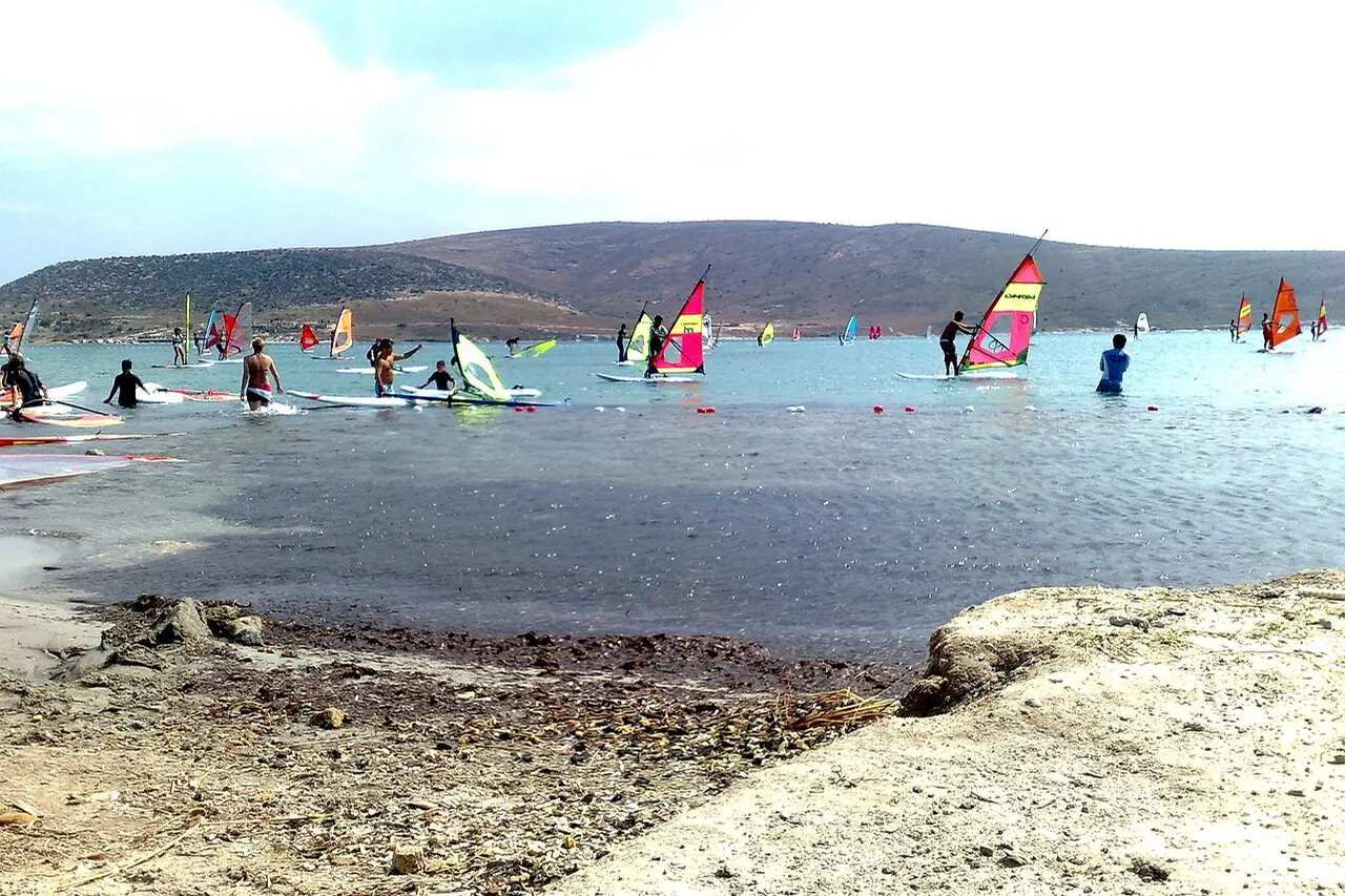 Windsurfer mit bunten Segeln vor der Küste von Alaçatı