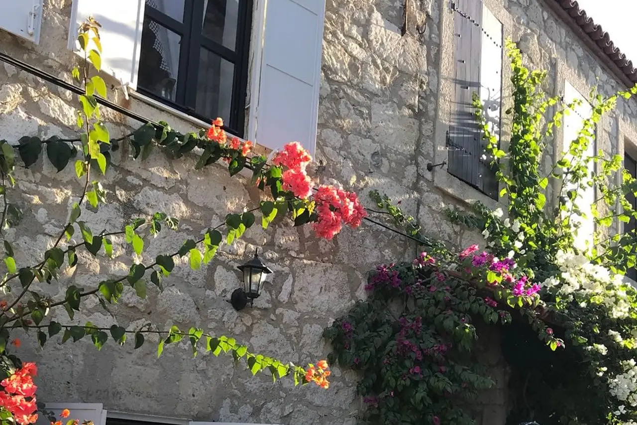 Steinhaus mit Blumen und Holzläden in Alaçatı
