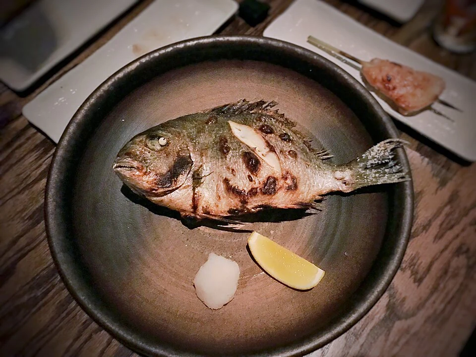 Grilled fish with lemon on a ceramic plate; illustrative food photograph