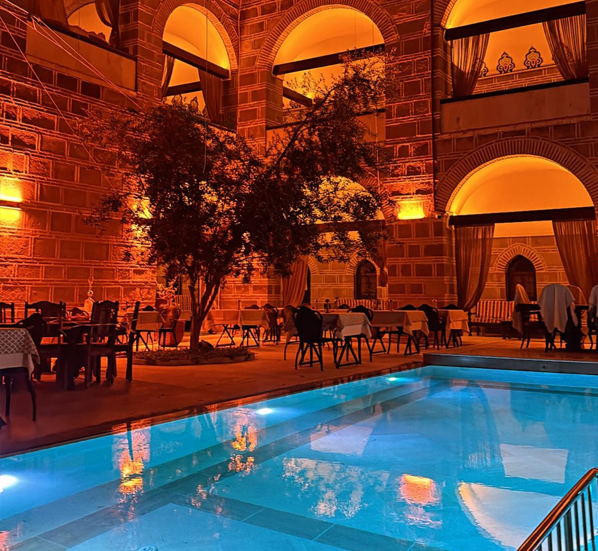 Kervansaray Antik Otel — Stone courtyard and pool in the evening