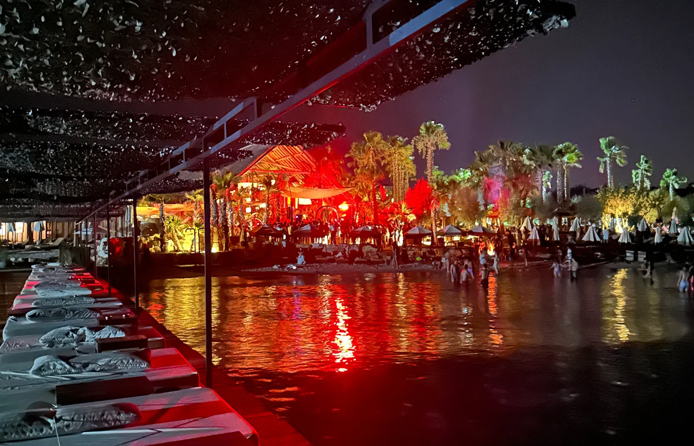 Fly-Inn Beach Club — Bar and seating with evening lighting